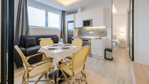 Ett kompakt bostadsutrymme med en matplats, ett litet kök och ett mindre sovrum.