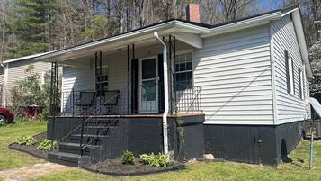 A single-story house with a front porch, a visible number '129' on the door, and a brick foundation.