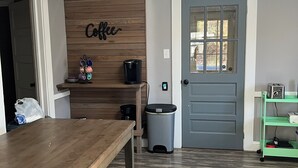 Une cuisine avec un mur en bois, un panneau indiquant « café », une machine à café et une poubelle.
