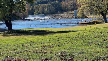 A river with a waterfall, surrounded by grassy areas and trees.