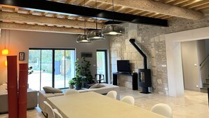 A spacious living area with a high ceiling, stone wall, and a fireplace. - Mas provençal, renovated by an architect, heated swimming pool. St Rémy de Provence (St Remy de provence)