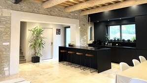 A modern kitchen with a black countertop, wooden beams, and a large window. - Mas provençal, renovated by an architect, heated swimming pool. St Rémy de Provence (St Remy de provence)