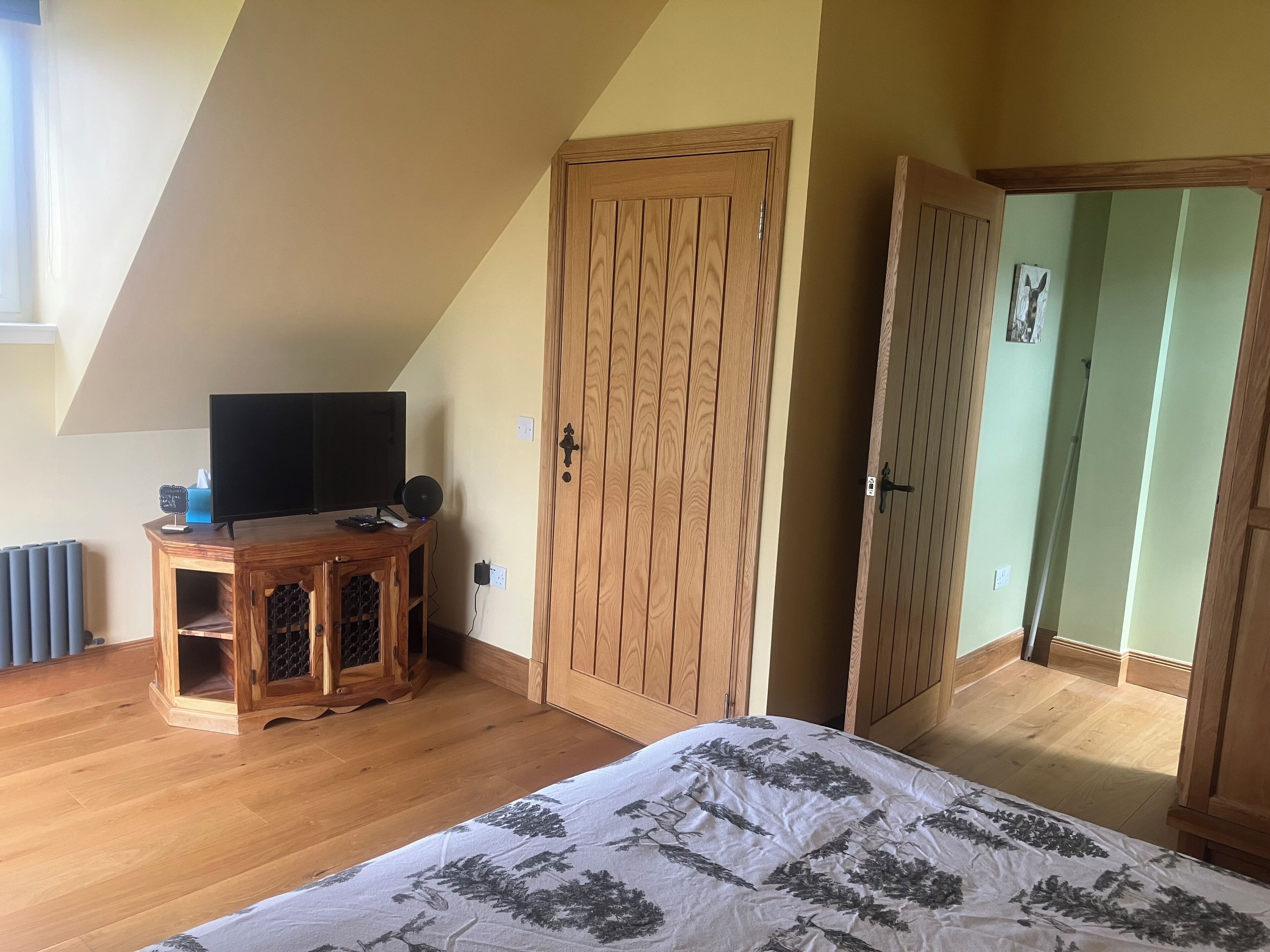 Une chambre à coucher avec un lit, une armoire en bois et un téléviseur posé sur un meuble en bois.