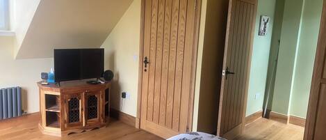 Une chambre à coucher avec un lit, une armoire en bois et un téléviseur posé sur un meuble en bois.