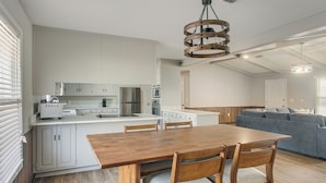 A modern kitchen with white cabinets, a wooden dining table, and a gray sofa in the living area. - Pond View, Fishing, BBQ, Fireplace, and More (Douglas)