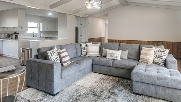 A modern living room with a grey sectional sofa, a round coffee table, and a patterned rug. - Pond View, Fishing, BBQ, Fireplace, and More (Douglas)