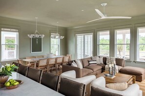 A spacious living area with a large sectional sofa, a dining table with chairs, and a ceiling fan. - Rare 7BR Coastal Retreat | Pool, Spa & Game Area (Bay St. Louis)