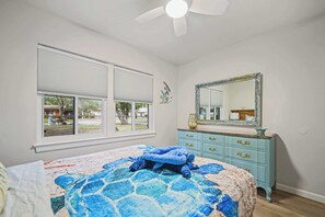 Une chambre à coucher avec un lit, une commode, un miroir et une fenêtre.