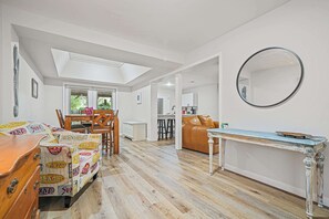 A spacious living area with a high ceiling, a dining table, a sofa, and a coffee table. - Coastal Home Family Friendly 2 Miles to Beach (Fort Walton Beach)
