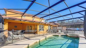 An indoor swimming pool with clear water, surrounded by a glass enclosure, and a yellow building with a tiled roof in the background. - Poolside Living: Family Retreat 12 Mi to Disney (Davenport)