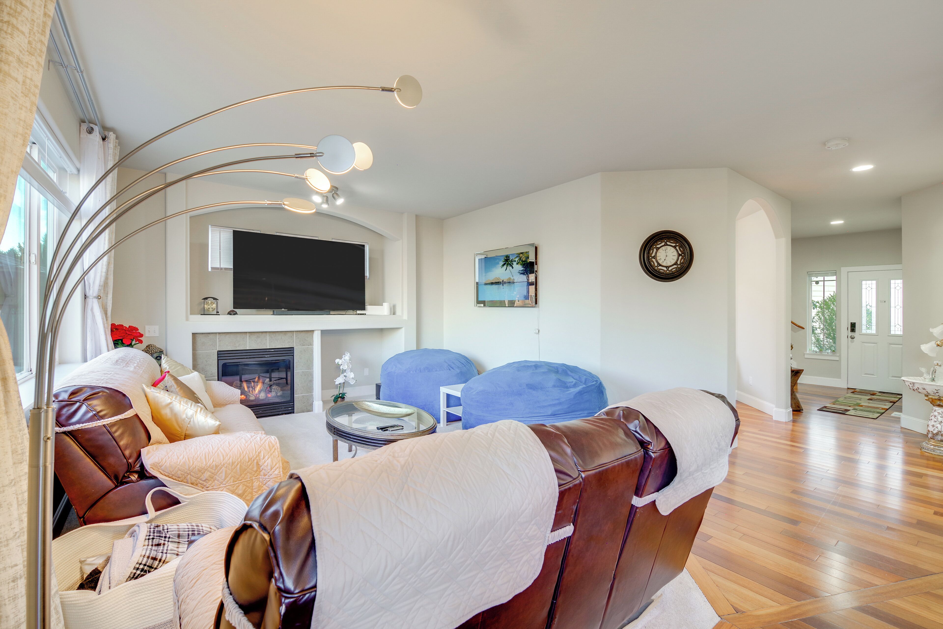 Un salon moderne avec une cheminée, un canapé en cuir, un fauteuil en forme de sac bleu et un téléviseur à écran plat.