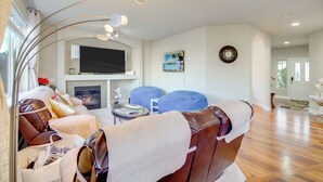 Uma sala de estar moderna com lareira, sofá de couro, puff azul e televisão de tela plana.
