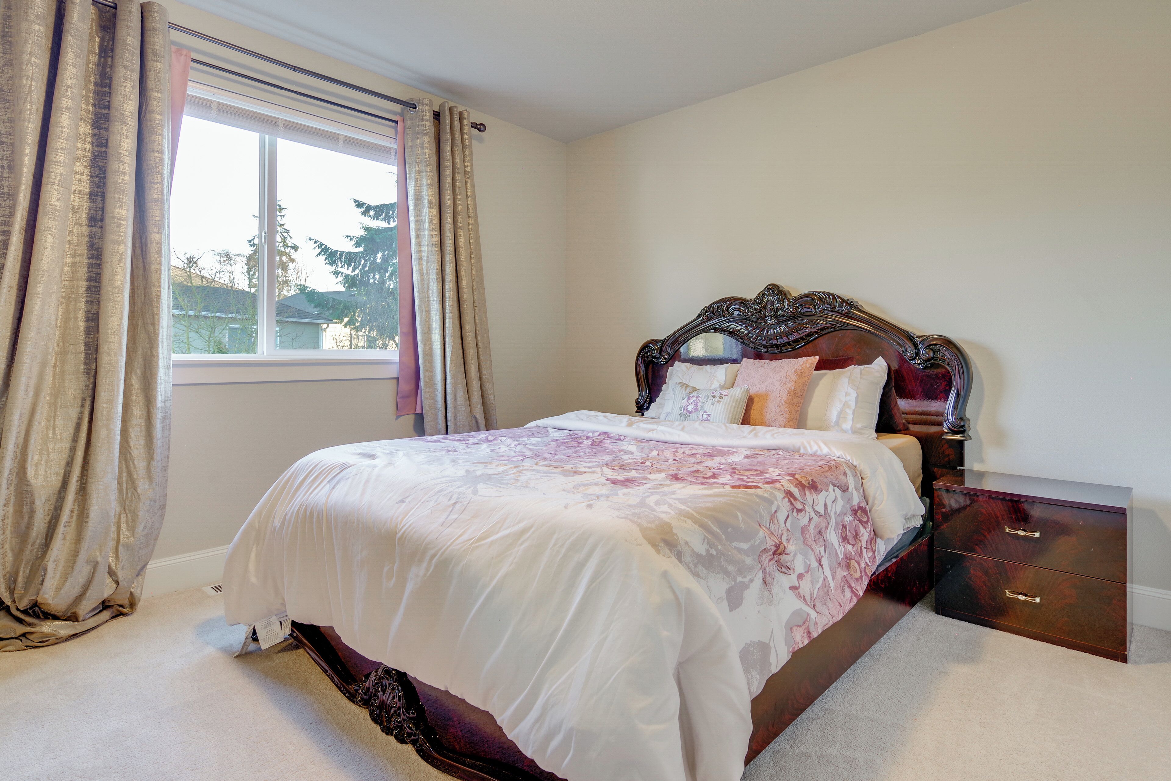 A bedroom with a large bed, a nightstand, and a dresser.