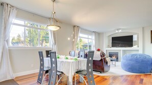 Uma sala de jantar com mesa posta para quatro pessoas, rodeada de cadeiras.