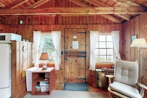 A wooden cabin interior with a kitchen area, a dining table, and a chair. - 3 Mi to Beach! Bay-View Northport Log Retreat (Northport)
