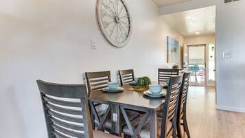 A dining area with a round table, six chairs, and decorative wall art.