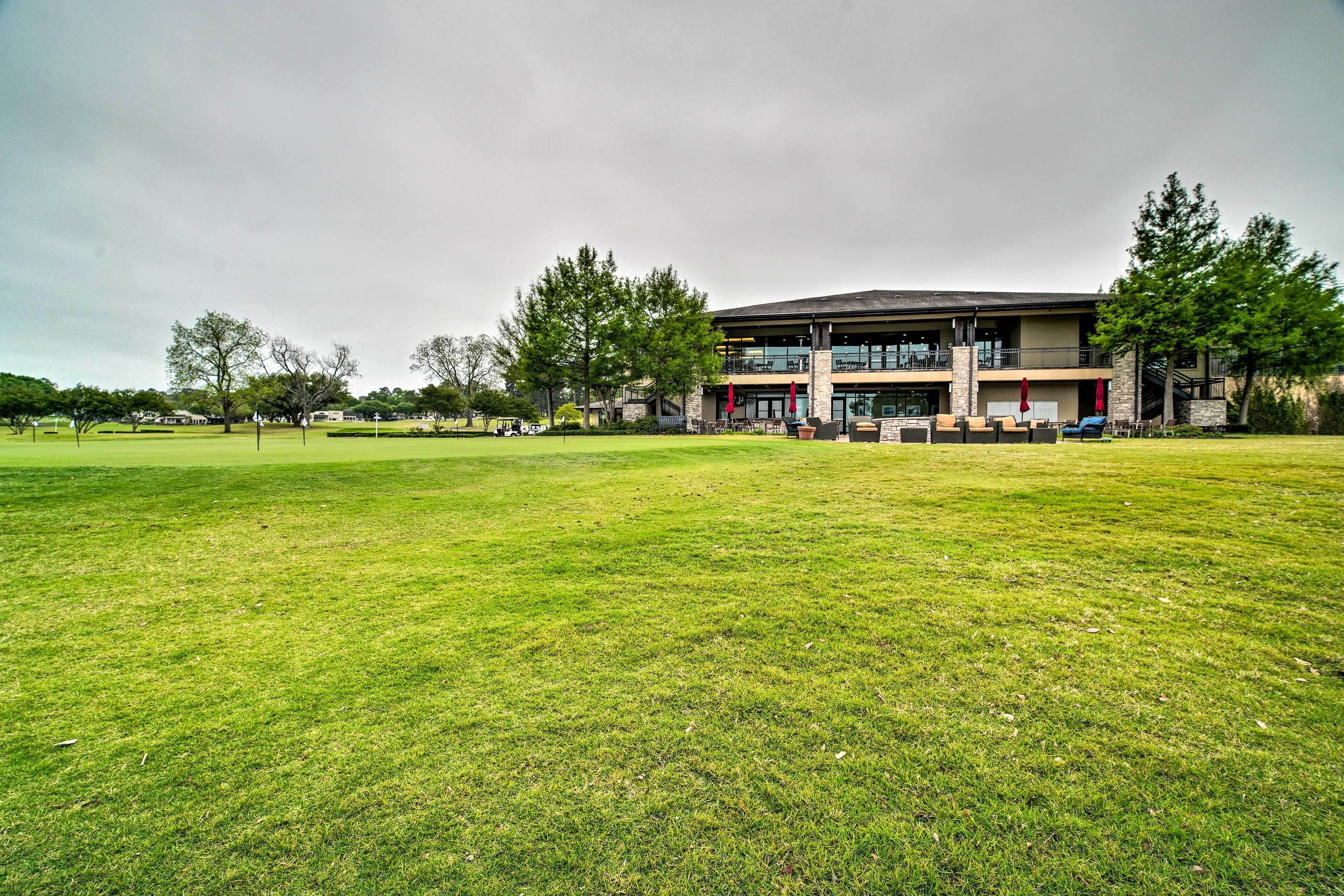 A modern building with a flat roof and large windows, surrounded by a well-maintained grassy area and trees.