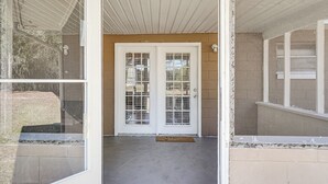 A view of a building entrance with a concrete floor, a white door with glass panels, and a brick wall. - Wooded Couple's Retreat w/ Lanai in Interlachen (Interlachen)