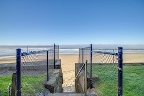 Een hek van gaasleed naar een strand met een heldere lucht.