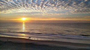 Una spiaggia con il sole che tramonta sull'oceano, creando un riflesso sull'acqua.