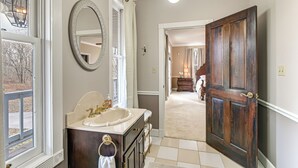 A bathroom with a large mirror, a sink, and a door leading to another room.
