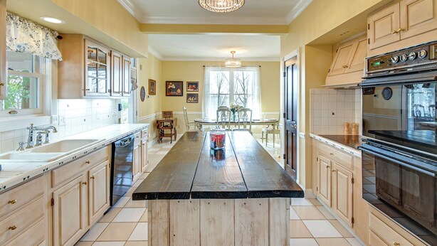 A kitchen with a central island, wooden cabinets, a large stove, and a chandelier.