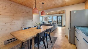 A modern kitchen with wooden cabinetry, a built-in refrigerator, and pendant lighting.