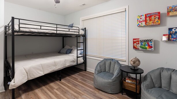 A bunk bed room with a ceiling fan, a window with blinds, and two bean bag chairs. - The Blue Herron of Carpenters Lake (Maceo)