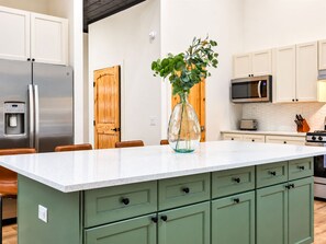 A kitchen with a central island, stainless steel appliances, and green cabinetry. - Pine Retreat | Hot Tub | Fire Pit Swings & Arcade (Broken Bow)