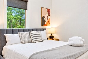 A hotel room with a bed, a nightstand, a lamp, and a painting on the wall. - Pine Retreat | Hot Tub | Fire Pit Swings & Arcade (Broken Bow)