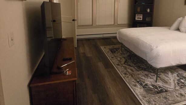 Una habitación de hotel con cama, escritorio, cómoda, alfombra y una lámpara en el techo.