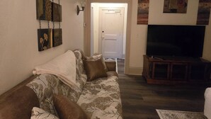 Una sala de estar con sofá, televisor y obras de arte en las paredes.