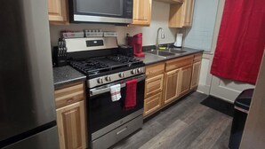 Una cocina con armarios de madera, un refrigerador de acero inoxidable, un microondas, una estufa y un lavamanos.