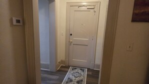 Un pasillo con alfombra estampada, una puerta blanca y una lámpara en el techo.