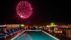 A swimming pool with lounge chairs and a Ferris wheel in the background.