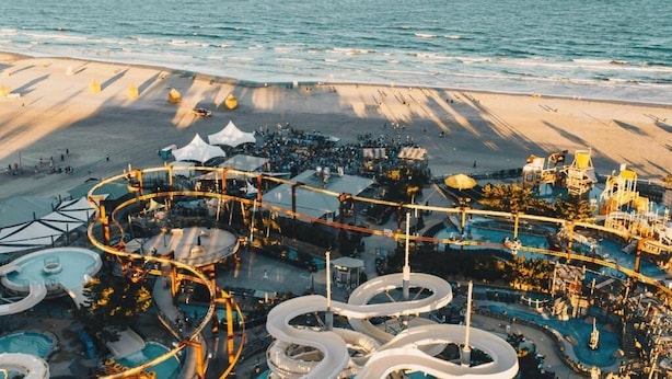 A resort with a water park, including slides and pools, adjacent to a beach.