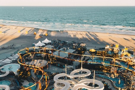 A resort with a water park, including slides and pools, adjacent to a beach.