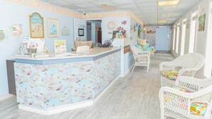 A reception area with a light blue wall, a reception desk, and wicker chairs.
