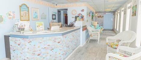 A reception area with a light blue wall, a reception desk, and wicker chairs.