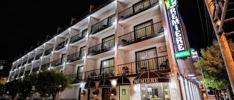 Un hotel de varios pisos con balcones, un llamativo letrero que dice "Premiere Motel" y una entrada visible.