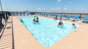 A pool area with multiple blue lounge chairs and a clear blue pool.