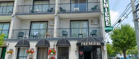 A multi-story hotel with balconies, a prominent 'Premiere Hotel' sign, and flower baskets on the facade.