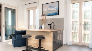 Eine moderne Küche mit einer Holztischinsel, zwei Barhocker, einer Spüle und einem großen Fenster.