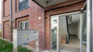 Ein Gebäudeeingang mit Briefkasten aus Metall, Glastüren und einer Ziegel fassade.