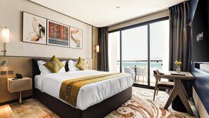 Une chambre d’hôtel avec un grand lit, un bureau et une vue sur la mer.