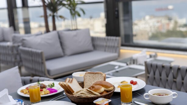 Une table dressée pour le petit-déjeuner, avec des assiettes, et une vue sur la ville.