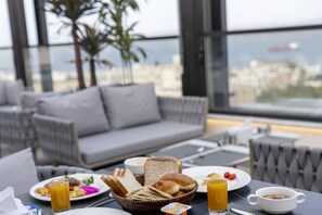 A breakfast setting with a table, plates, and a view of the city. - April Hotel (Aqaba)