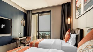 Une chambre d’hôtel avec deux lits, un bureau et une télévision.