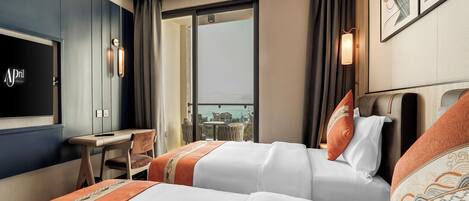 A hotel room with two beds, a desk, and a TV.