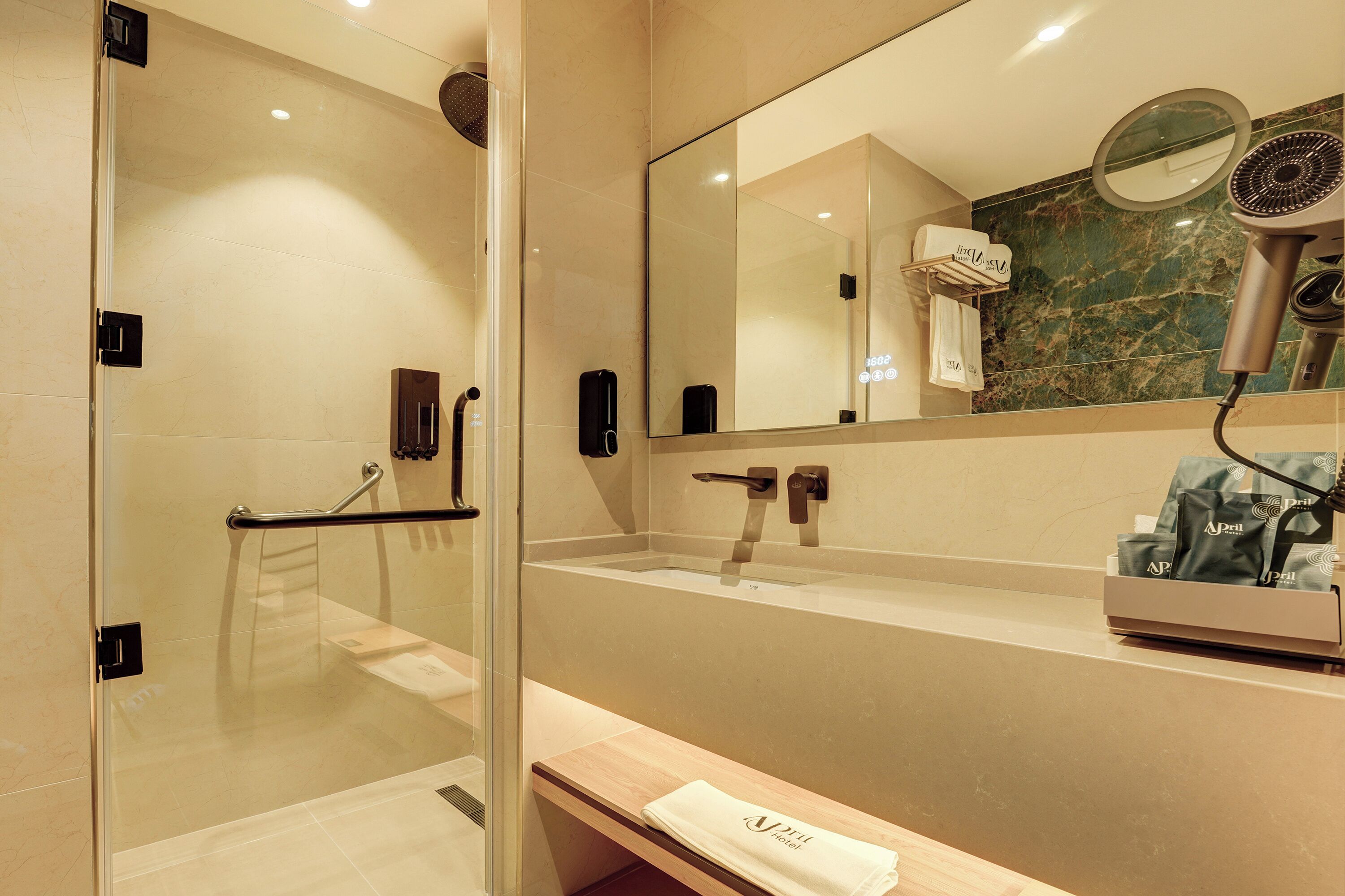 A modern bathroom with a glass shower enclosure, a vanity with a sink, a mirror, and a hairdryer on the counter.